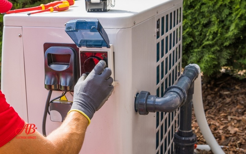 AB Electrical Services Person wearing gloves adjusts settings on an outdoor HVAC unit. Orange County CA