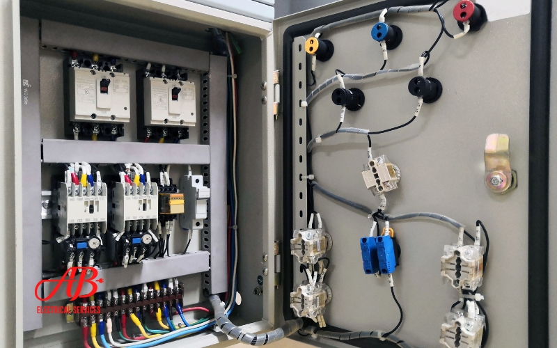 AB Electrical Services An open electrical control panel reveals a network of wires, switches, and components intricately connected inside. Featuring an "AB" logo in red, this panel is ready to house an Automatic Transfer Switch for seamless power management. Orange County CA